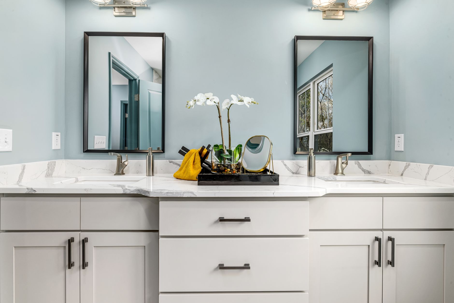 A serene modern bathroom featuring twin sinks, elegant faucets, and decorative mirrors in Temecula, CA