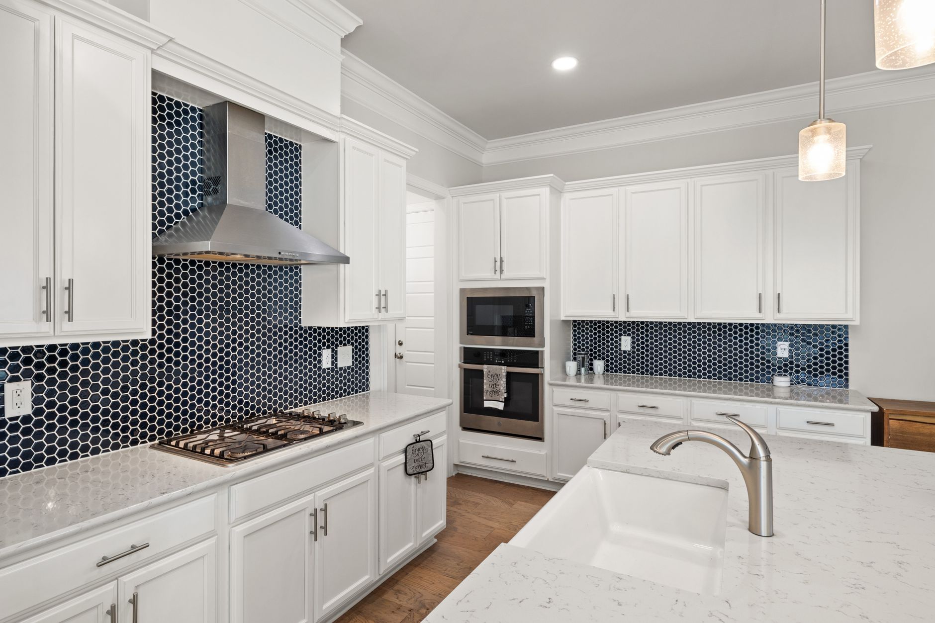 Elegant white kitchen featuring a modern design with blue hexagonal tile backsplash and stainless steel in Temecula, CA